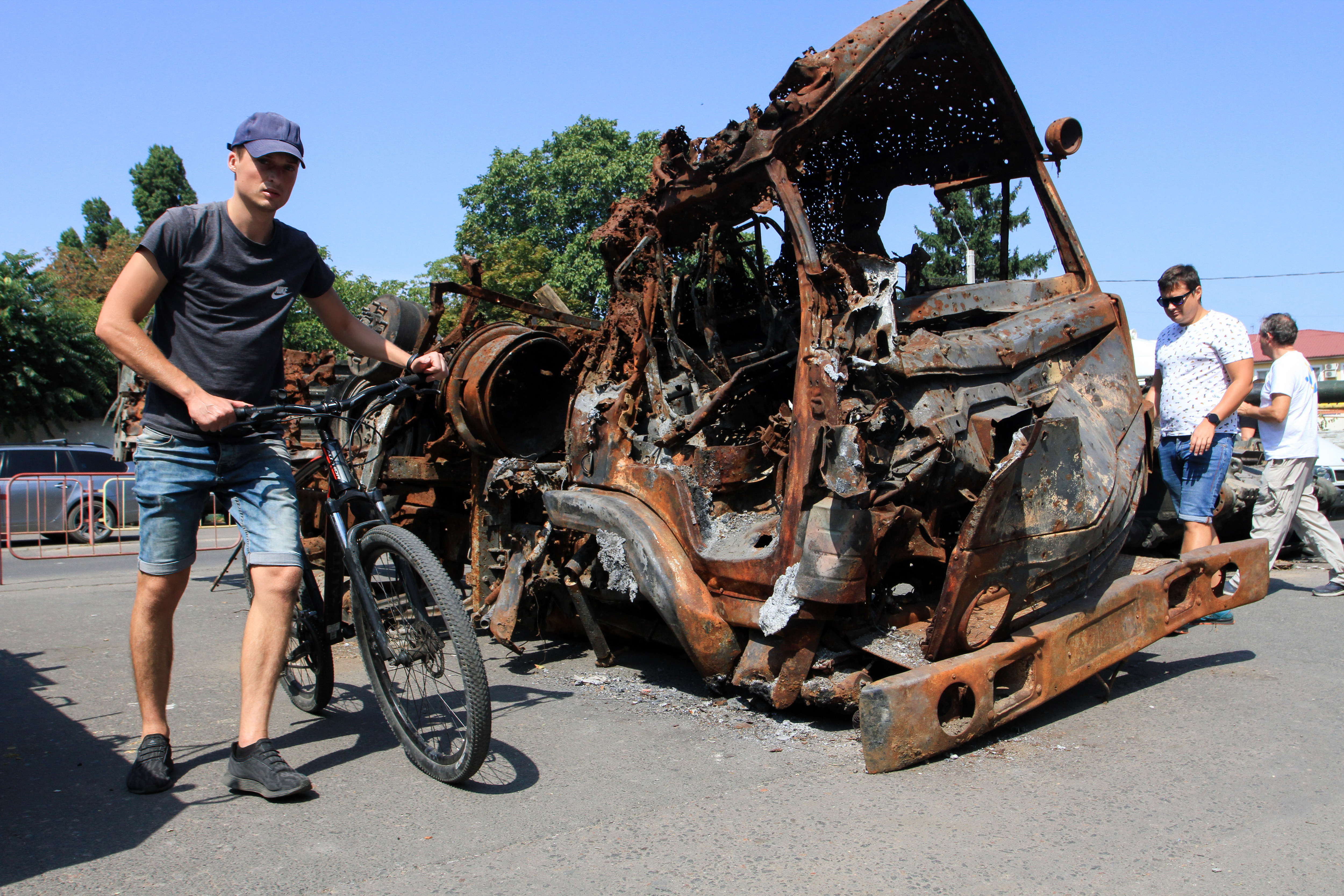 ODESSA, UKRAINE - 2022/08/27: A man with a bicycle passes by a burned-out KAMAZ truck. Units of the operational command "South" of the Armed Forces of Ukraine brought Russian military equipment burned in the battles for the independence of Ukraine for display. The T-90 tank, two transporters MT-LB, Kamaz, and armored personnel carrier are exhibited. (Photo by Viacheslav Onyshchenko/SOPA Images/LightRocket via Getty Images)