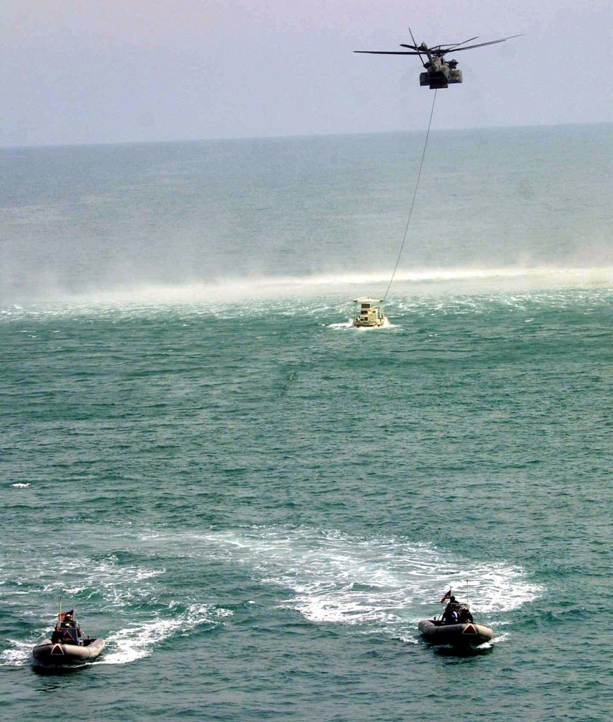 A US MH-53E military helicopter drags a MK 106 Combination escorted by two military Zodiak boats during an opperation off the USS Ponce to clear mines from Khor Abdullah at the entrance to Umm Qasr port in the western Gulf 29 March 2003. Sharp differences have emerged between the United States and Britain on who should rebuild Iraqi port Umm Qasr after the war, as non-US firms have been almost completely excluded from the tenders process. Umm Qasr is Iraq's only deep-water seaport on its short Gulf coastline, which lies on the western side of the Fao Peninsula 460 kilometers (280 miles) south of Baghdad. AFP PHOTO/Rabih MOGHRABI (Photo by RABIH MOGHRABI / AFP) (Photo by RABIH MOGHRABI/AFP via Getty Images)