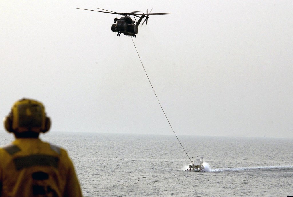 This photo released by the US Navy 26 March, 2003, shows an MH-53 Sea Dragon helicopter from the "Vanguards" of Helicopter Mine Countermeasures Squadron Fourteen pulling a Mark 105 Magnetic Influence Minesweeping System (SLED) towards the welldeck of the amphibious transport dock ship USS Ponce, after mine countermeasures operations near the mouth of the Khawar Abd Allah Delta 24 March. The Ponce is deployed in support of Operation Iraqi Freedom. AFP PHOTO/US NAVY-BOB HOULIHAN (Photo by BOB HOULIHAN / NAVY VISUAL NEWS / AFP) (Photo by BOB HOULIHAN/NAVY VISUAL NEWS/AFP via Getty Images)