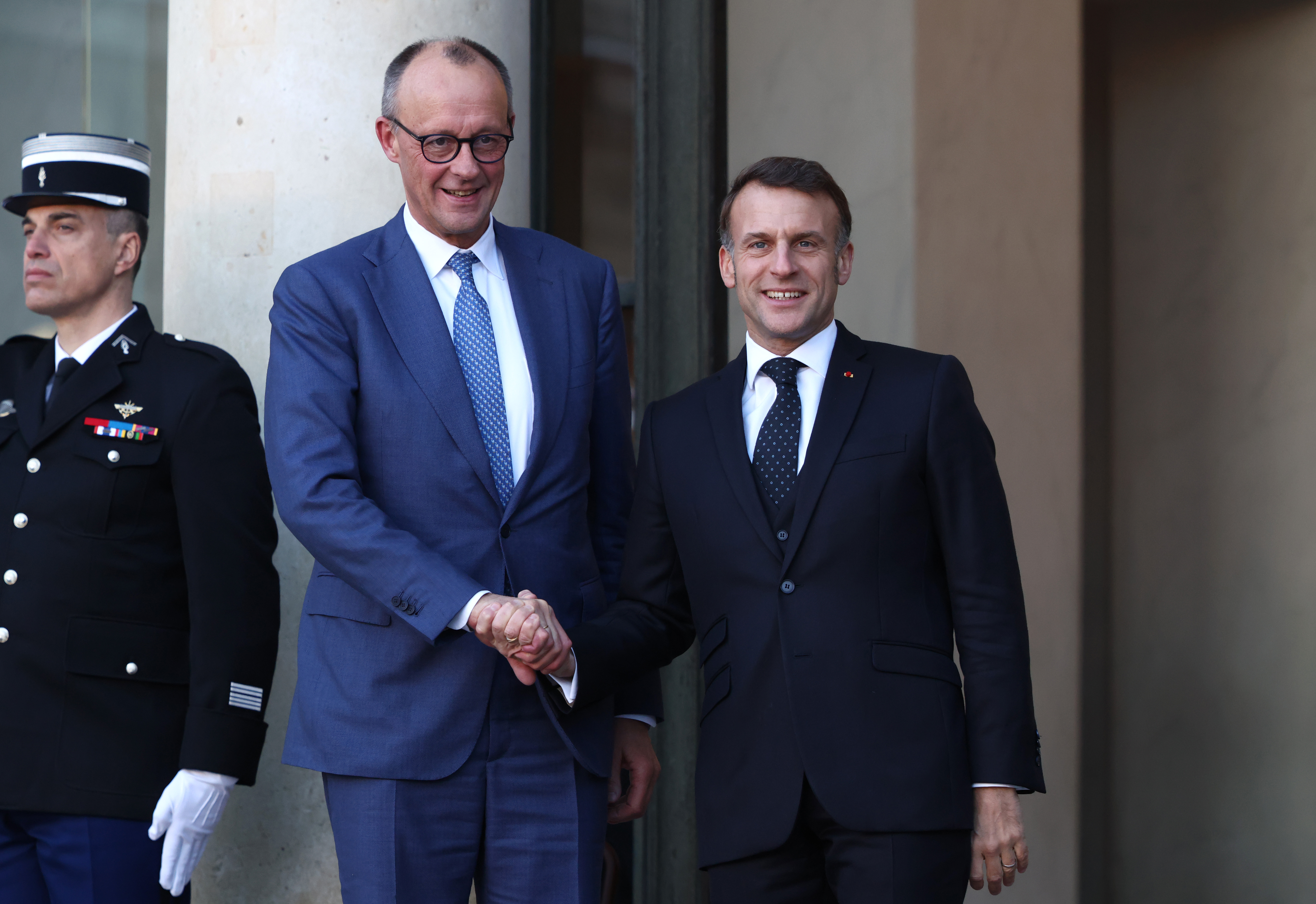 PARIS, FRANCE - JANUARY 06: French President Emmanuel Macron (R) greets German Chancellor Friedrich Merz upon his arrival at the Elysee Palace on January 06, 2026 in Paris, France. Leaders from around 30 countries are gathering in Paris to discuss military support for Ukraine, amid ongoing negotiations on a US-brokered peace plan to end Russia's war in Ukraine. (Photo by Tom Nicholson/Getty Images)