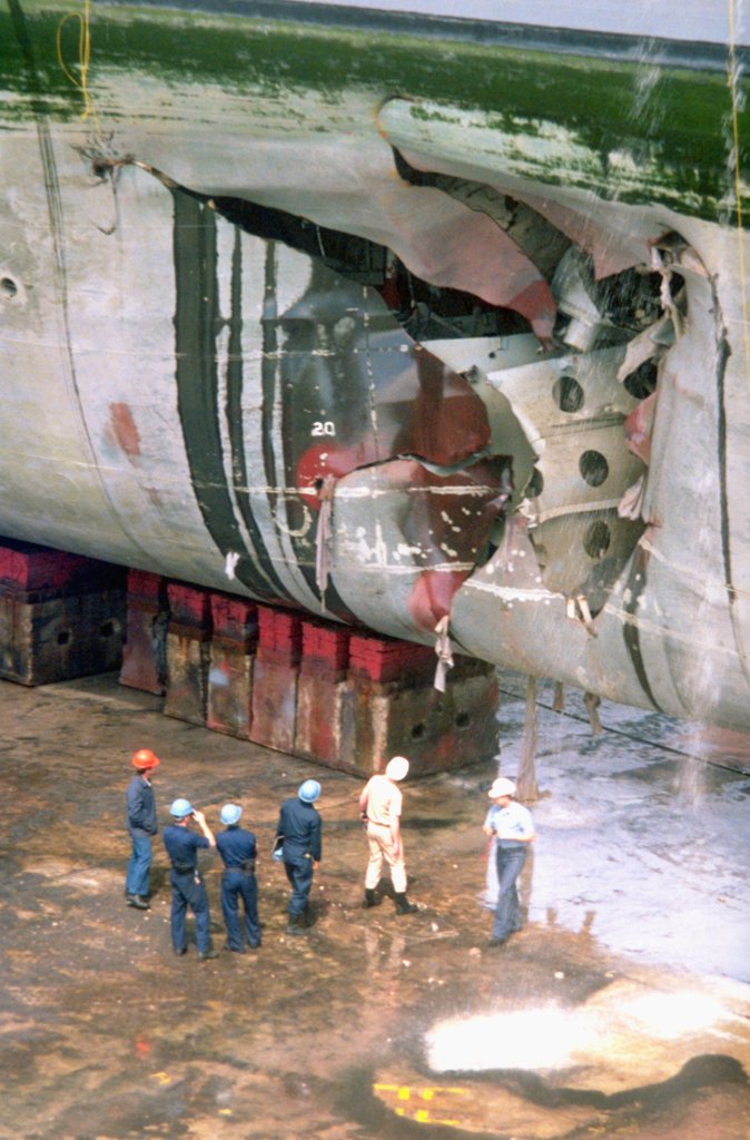The amphibious assault ship USS Tripoli (LPH-10) lies in dry dock for repairs to a hole in its starboard bow caused by an Iraqi mine. The Tripoli struck the mine on February 18 while serving as a mine-clearing platform in the northern Persian Gulf during Operation Desert Storm. The ship was able to continue operations after damage control crews stopped the flooding caused by the explosion. (Photo by © CORBIS/Corbis via Getty Images)
