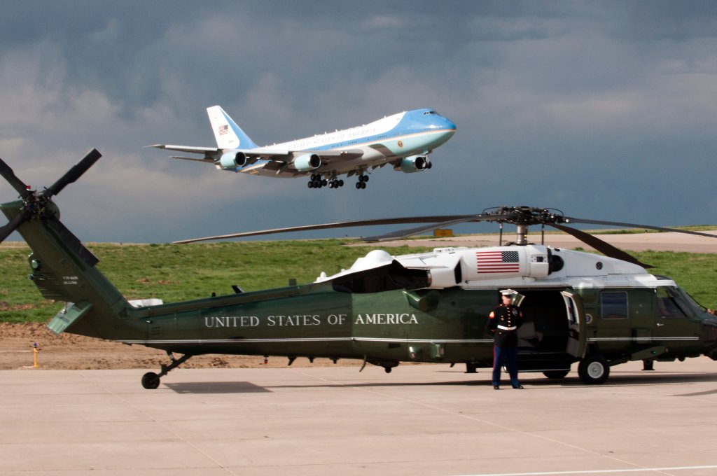A U.S. Marine stands at ease next to a VH-60N Whitehawk executive transport helicopter as Air Force One lands at Buckley Air Force Base, Colo., April 24, 2012. President Obama is visiting the University of Colorado at Boulder to talk to students about a looming spike in student loan interest rates.