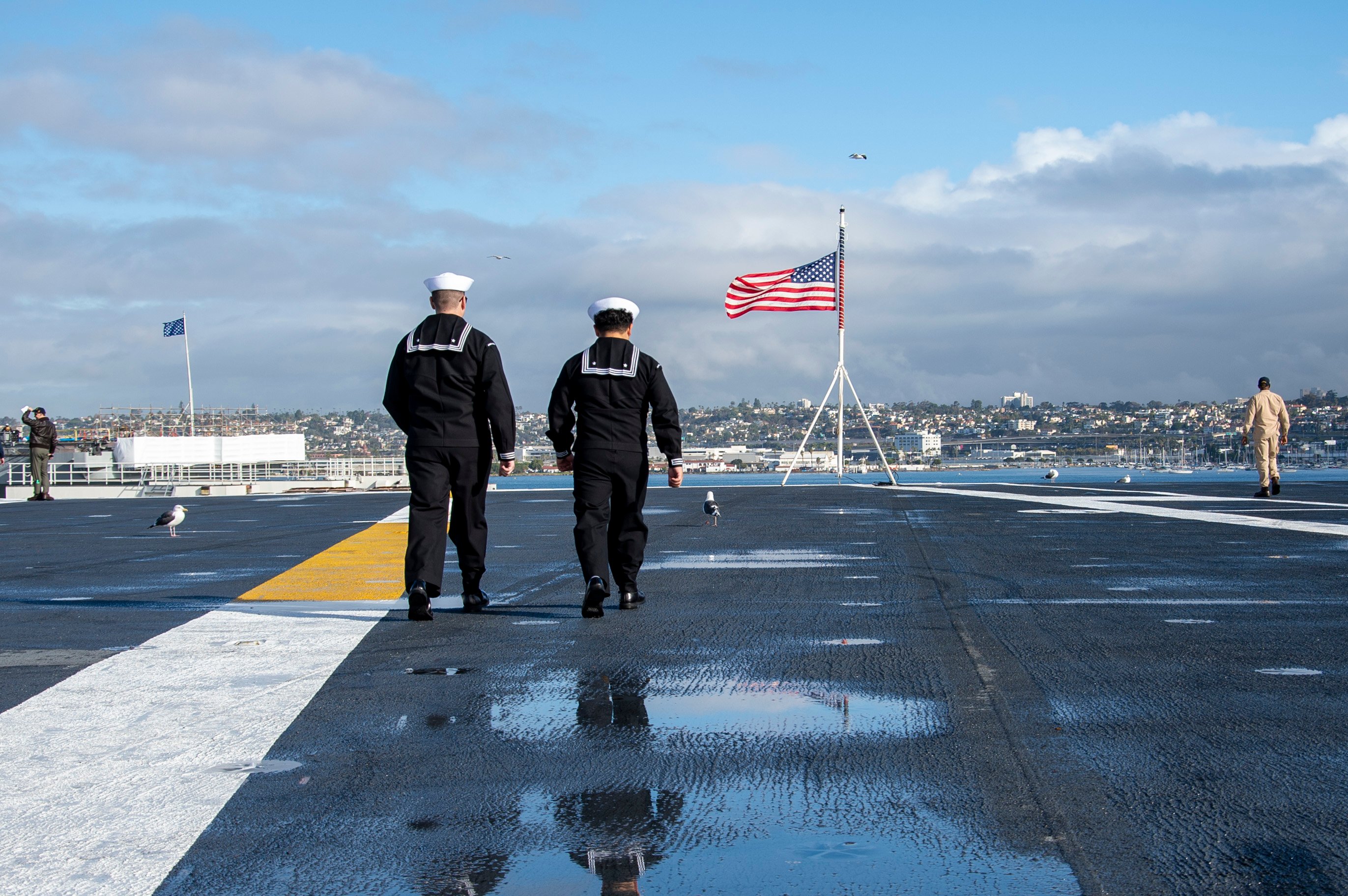 U.S. Navy Aviation Ordnanceman 3rd Class Gabriel Edens, left, and U.S. Navy Aviation Ordnanceman 3rd Class Sergio Vela prepare to shift colors on the flight deck of Nimitz-class aircraft carrier USS Abraham Lincoln (CVN 72) on Nov. 21, 2025. Abraham Lincoln is currently moored at Naval Station North Island. (U.S. Navy photo by Mass Communication Specialist 3rd Class Mario Castro Gamez)