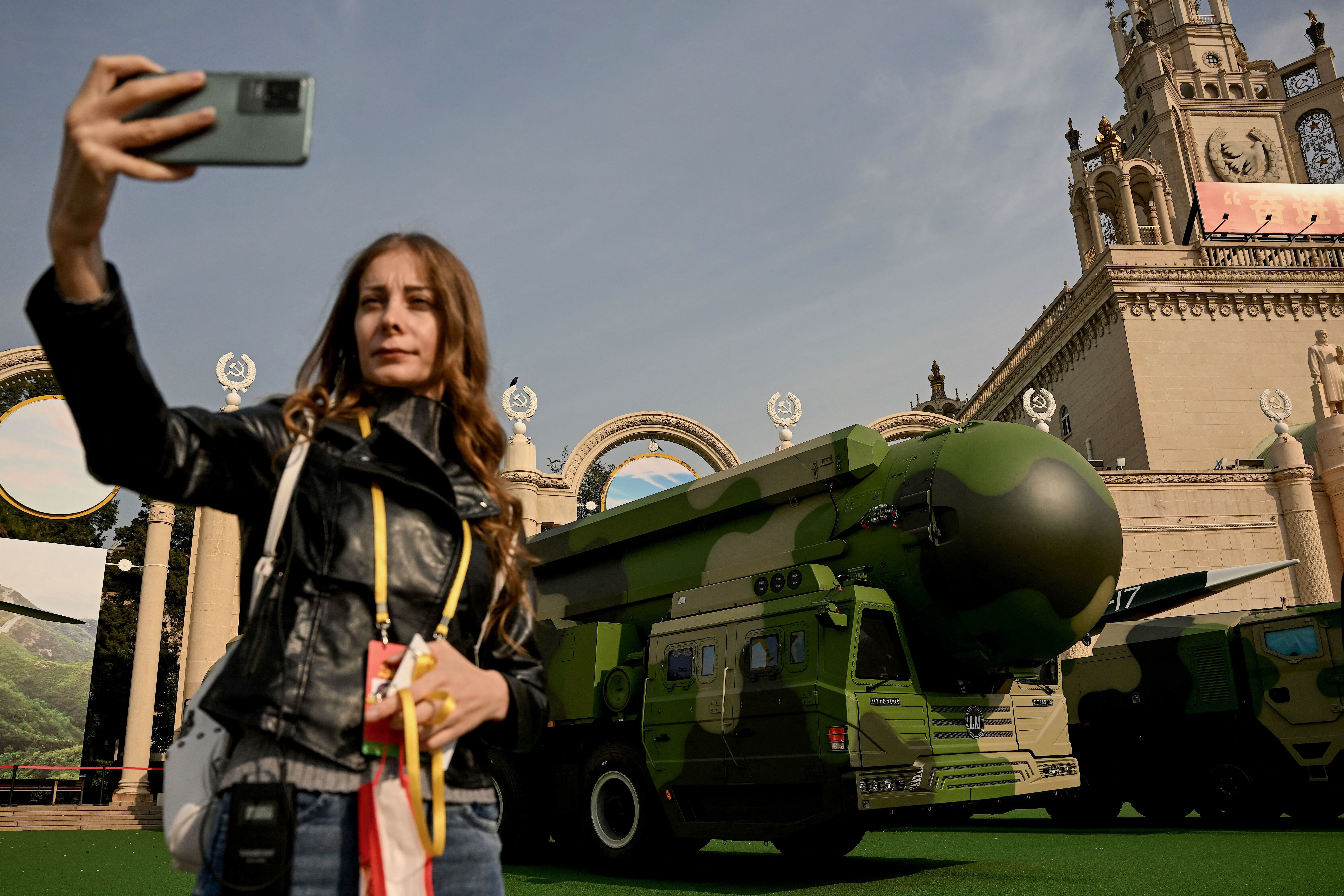 A woman uses a mobile phone to take a selfie in front of the Dongfeng-41 (DF-41), an intercontinental ballistic missile on display, at the Beijing Exhibition Center, where an exhibition entitled "Forging Ahead in the New Era" showing the country's achievements during China's President Xi Jinping's past two terms is currently ongoing, ahead of the 20th Communist Party Congress meeting in Beijing on October 12, 2022. (Photo by Noel CELIS / AFP) (Photo by NOEL CELIS/AFP via Getty Images)