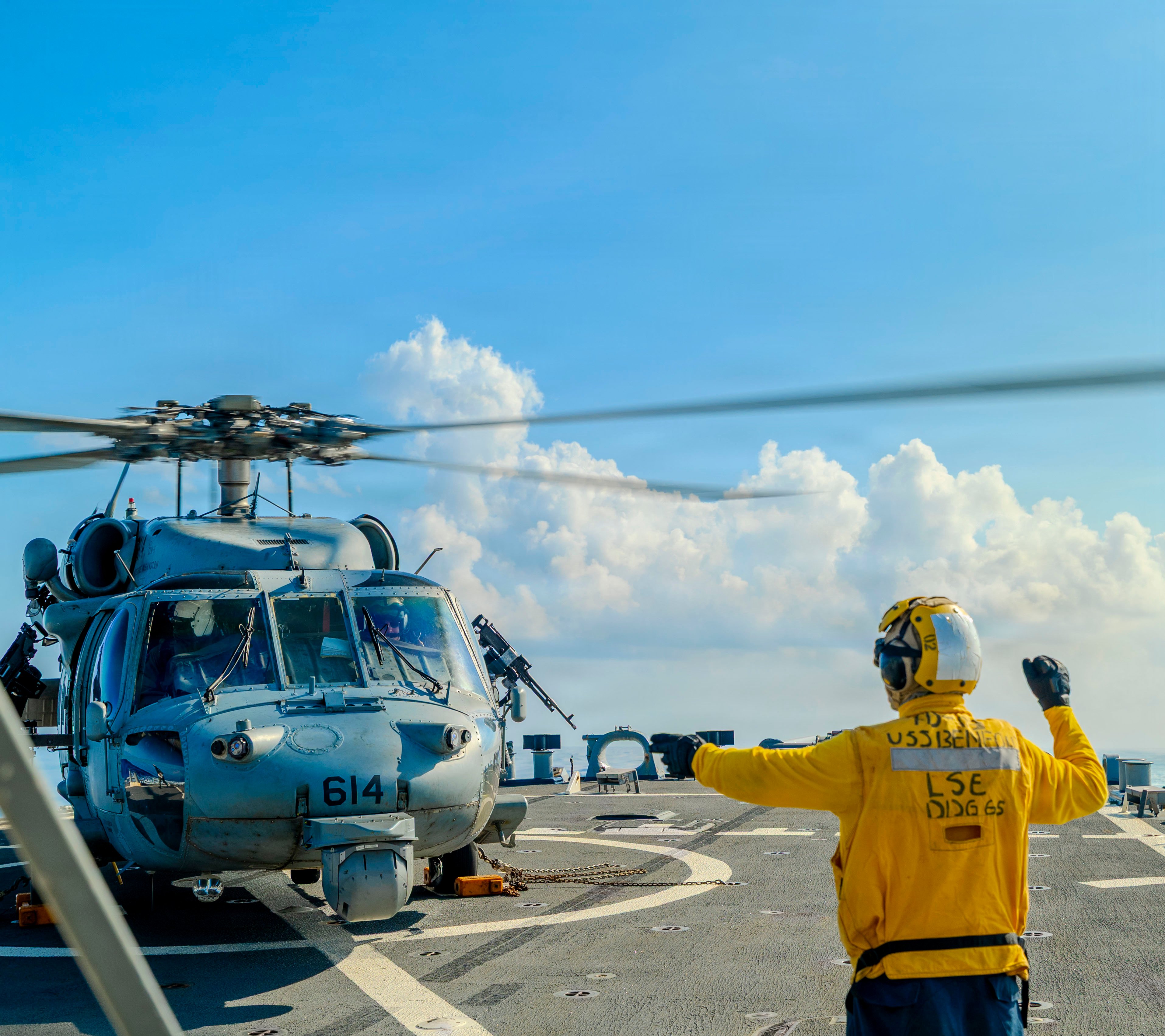 260723-N-JJ672-1063 U.S. Navy Boatswain’s Mate Seaman Eduardo Ramirez Lopez, from California, directs an MH-60S Seahawk helicopter assigned to Helicopter Sea Combat Squadron (HSC) 12 attached to Nimitz-class aircraft carrier USS George Washington (CVN 73) aboard Arleigh Burke-class guided-missile destroyer USS Benfold (DDG 65) while conducting flight quarters in the South China Sea, July 23, 2026. Benfold is forward deployed and assigned to Task Force 70 and Carrier Strike Group 5. Task Force 70 and CSG 5 are forward-deployed to the U.S. 7th Fleet area of operations in support of a free and open Indo-Pacific region. U.S. 7th Fleet is the Navy’s largest forward-deployed numbered fleet, and routinely interacts and operates with allies and partners in preserving a free and open Indo-Pacific. Photograph toned for effect. (U.S Navy photo by Mass Communication Specialist 2nd Class Oscar Diaz)