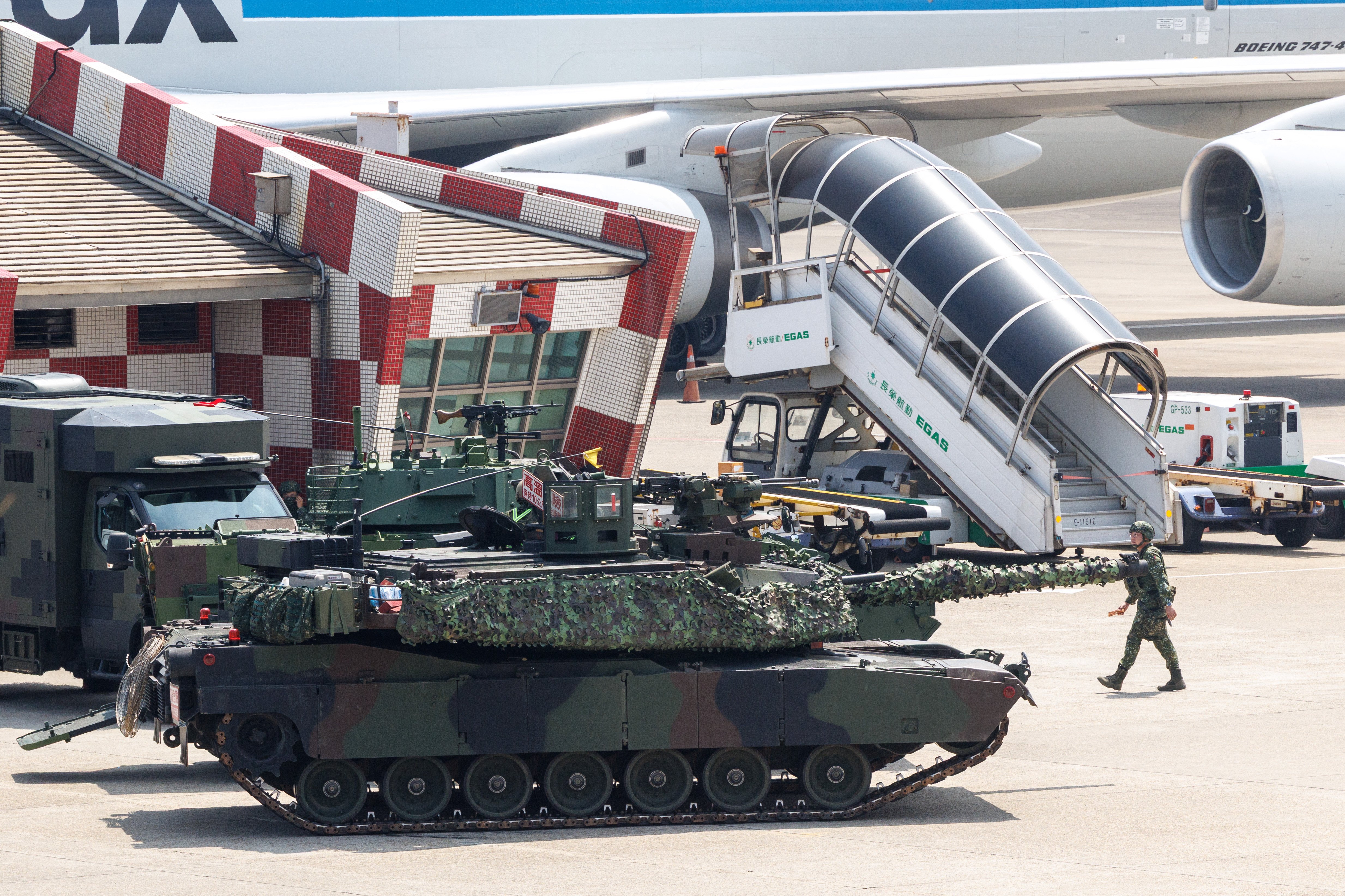 A Taiwanese military M1A2T tank is pictured next to aircraft during a drill simulating an enemy airborne assault at Taiwan Taoyuan International Airport in Taoyuan on August 7, 2026. Taiwan's largest military drills of the year began on August 5 as the island democracy attempts to prepare its population for a potential Chinese invasion. (Photo by CHENG Yu-chen / AFP via Getty Images)