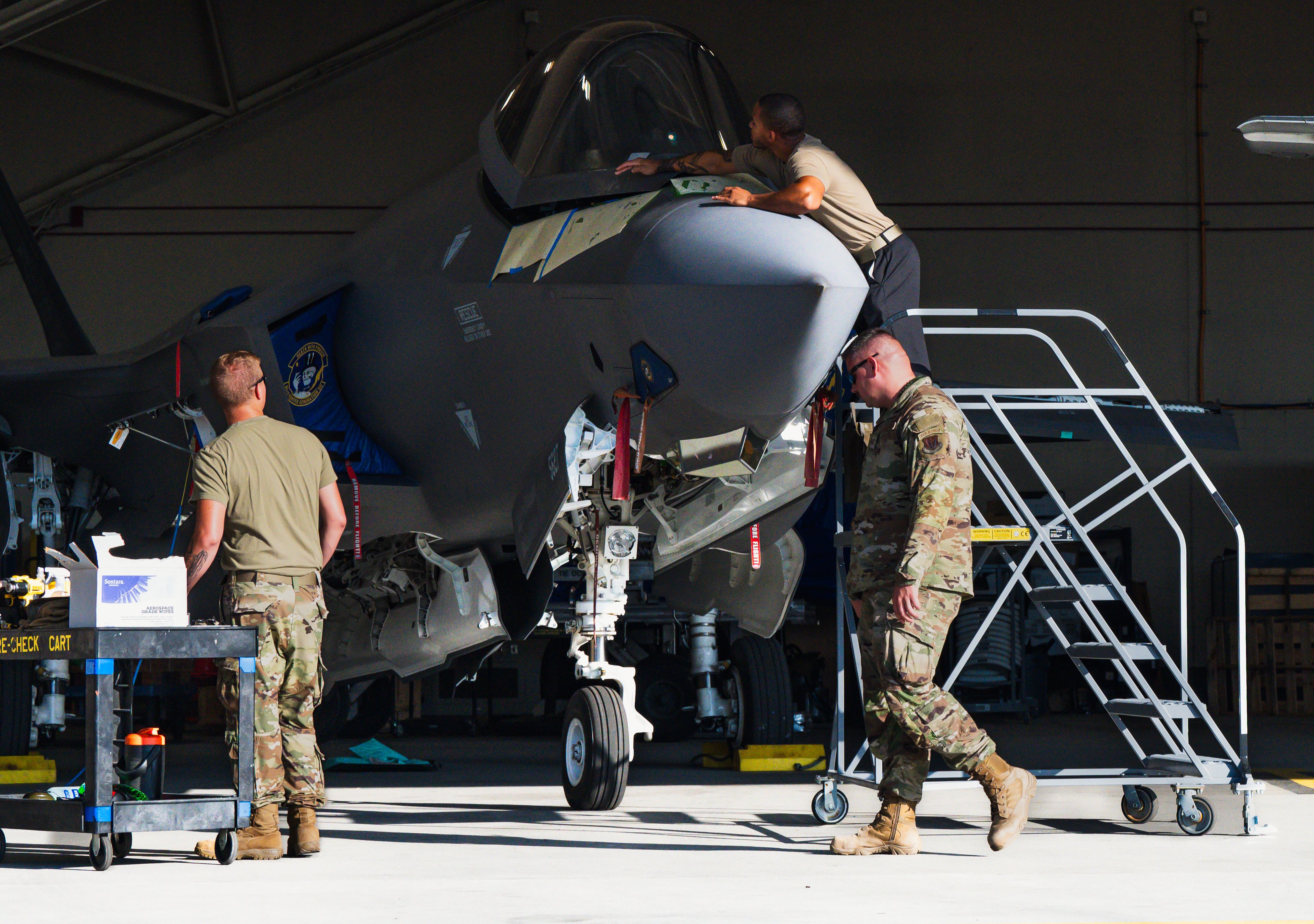 U.S. Air Force Staff Sgt. Ossoren Kade, left, and Tech. Sgt. Ryan McGarrigle shares information with Senior Airman Tyrese Baylis, 325th Maintenance Squadron low observable maintainers, as he works on an F-35A Lightning II at Tyndall Air Force Base, Florida, Aug. 16, 2024. Low observability is a complex system that goes far beyond simply painting an aircraft. LO requires a specialized and intricate technique that is essential for the F-35A to remain undetectable in contested areas. (U.S. Air Force photo by Airman 1st Class Victoria Moehlman)