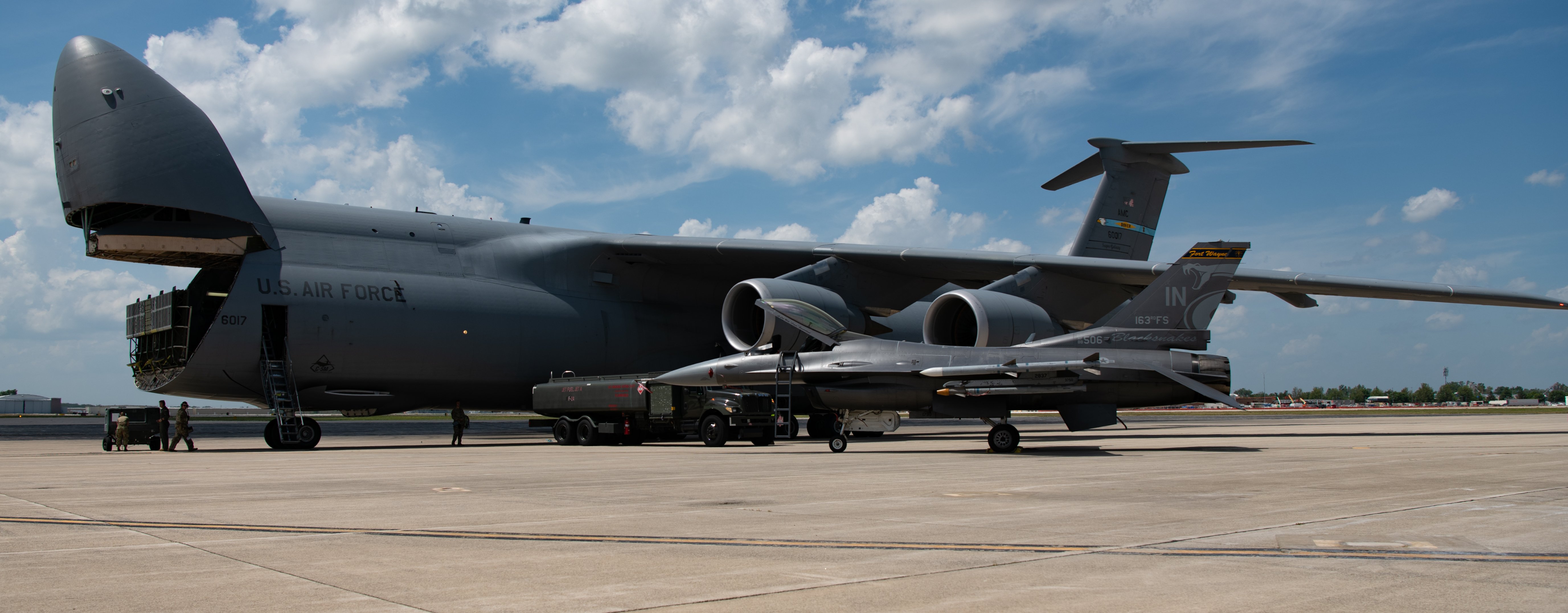 A U.S. Air Force C-5M Super Galaxy aircraft assigned to the 9th Airlift Squadron, Dover Air Force Base, left, sits beside an R-11 fuel truck and an F-16C Fighting Falcon aircraft assigned to the 122nd Fighter Wing on the flight line at the 122nd Fighter Wing, Fort Wayne, Indiana, July 24, 2025. The C-5 participated in an agile combat employment exercise that included wet wing defueling to the fuel truck which then provided fuel to the F-16. (U.S. Air National Guard photo by Tech. Sgt. David Sherman)
