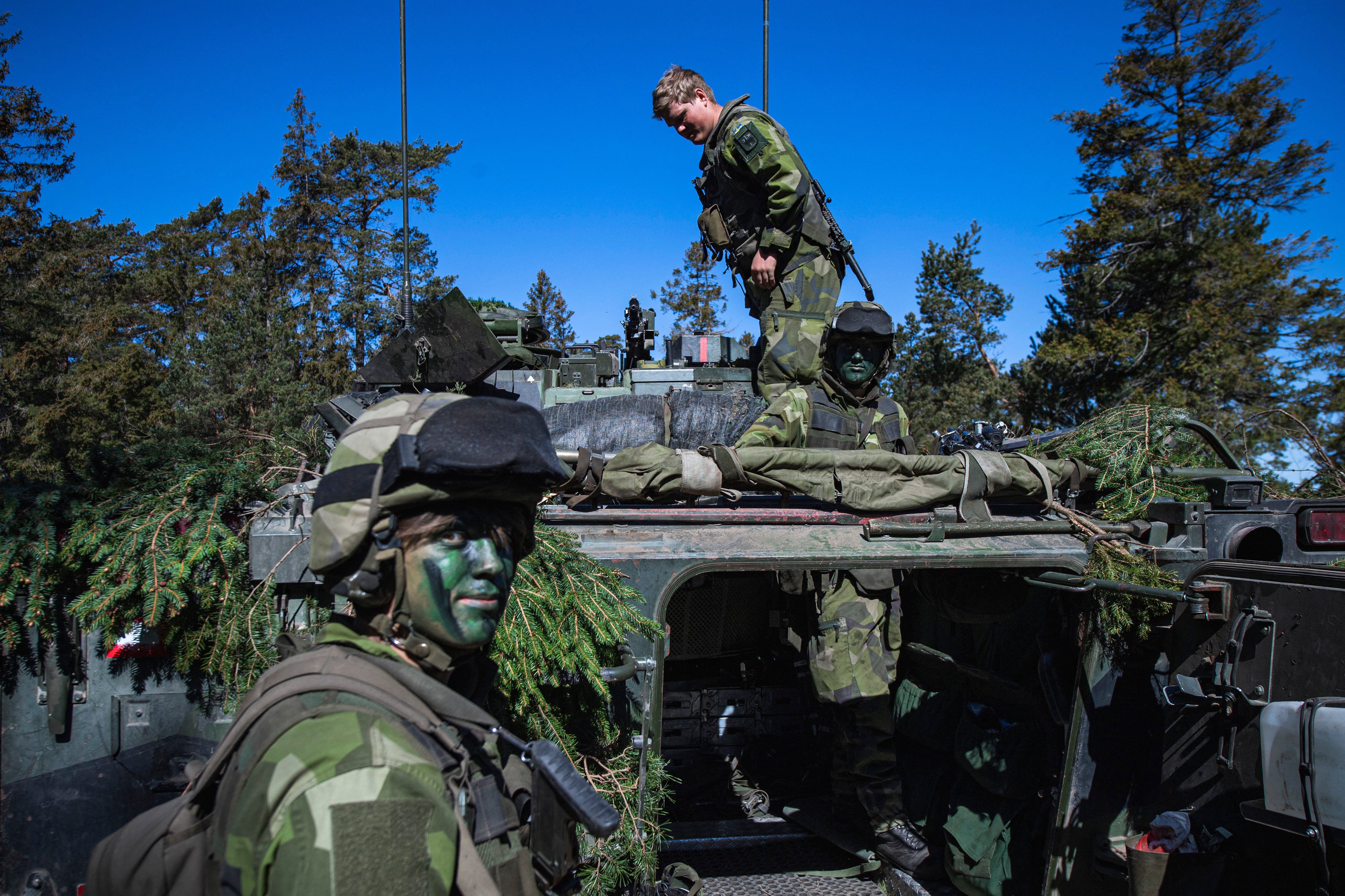 Soldiers of the P18 Gotland Regiment of the Swedish Army camouflage an armoured vehicle during a field exercise near Visby on the Swedish island of Gotland on May 17, 2022. Finland and Sweden are expected to announce this week whether to apply to join NATO following Russia's Ukraine invasion, in what would be a stunning reversal of decades-long non-alignment policies. On Sweden's strategically-located Baltic Sea island of Gotland, Home Guard troops were last week called in for a special month-long training exercise, coinciding with annual military exercises taking place across Finland and Sweden next week. (Photo by Jonathan NACKSTRAND / AFP) (Photo by JONATHAN NACKSTRAND/AFP via Getty Images)
