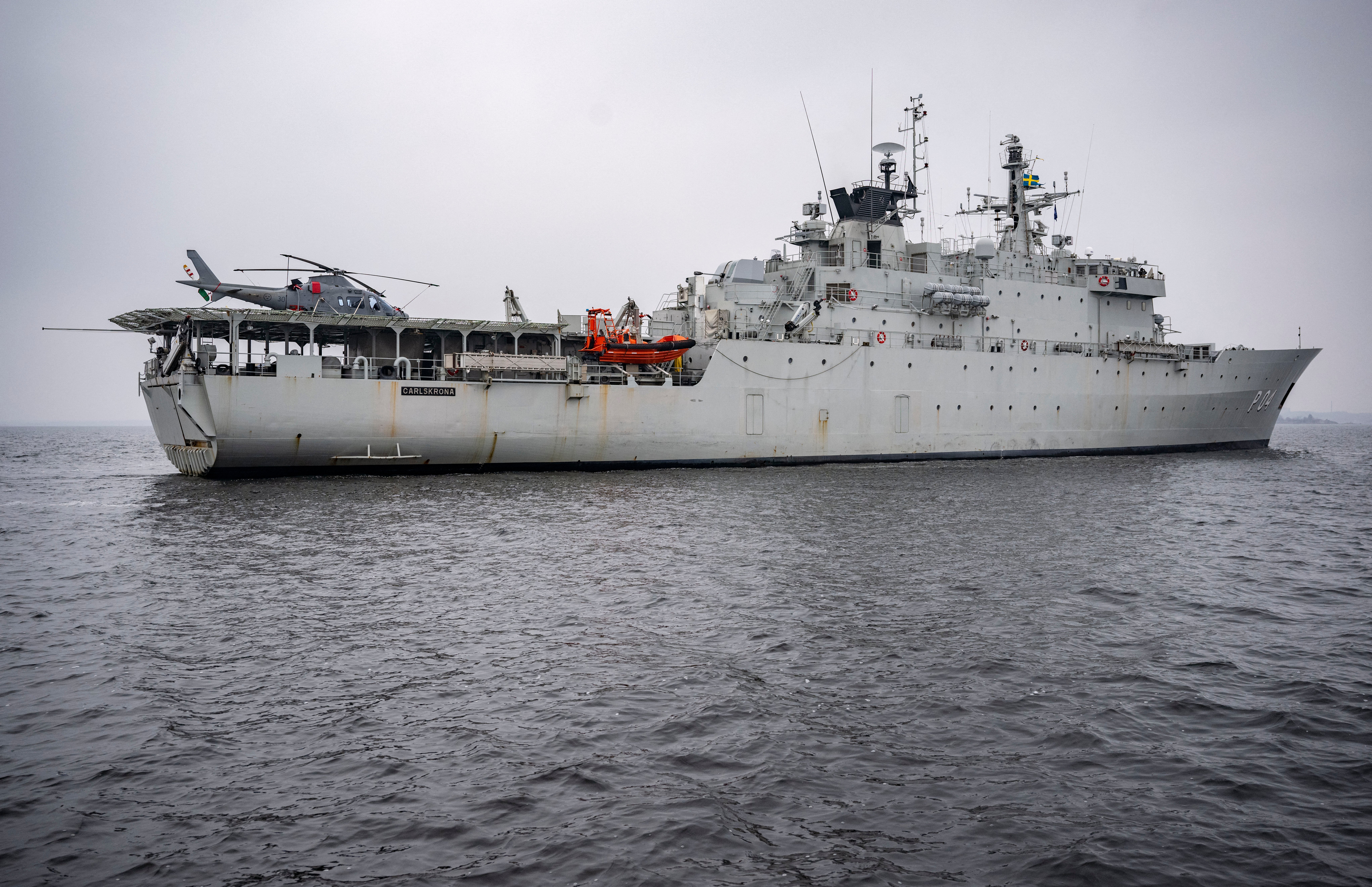A picture taken on February 4, 2025 shows a Helicopter 15 (HKP15) (L) on the flight deck of patrol ship HMS Carlskrona (P04) on open water near Karlskrona, Sweden, as part of the NATO Baltic Sea patrol mission, the Baltic Sentry, aimed to secure critical underwater infrastructure. The patrol ship HMS Carlskrona (P04) set off from the naval port in Karlskrona on February 4, 2025 to become part of NATO's Baltic Sentry operation as one of several Swedish ships that are part of Standing NATO Maritime Group One (SNMG1). This is the first time the ship has hoisted the NATO flag on board. The purpose of NATO's Baltic Sentry operation is to demonstrate presence and secure critical underwater infrastructure. (Photo by Johan NILSSON / TT NEWS AGENCY / AFP) / Sweden OUT (Photo by JOHAN NILSSON/TT NEWS AGENCY/AFP via Getty Images)