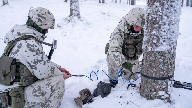Finnish conscripts wearing winter camouflage uniforms install anti personnel mines on a tree in a snow covered forest during a media day event at the Kainuu Brigade, a Finnish Army unit in Kajaani, Finland, on February 3, 2026.