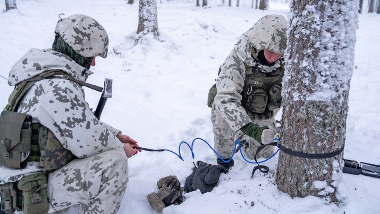 Finnish conscripts wearing winter camouflage uniforms install anti personnel mines on a tree in a snow covered forest during a media day event at the Kainuu Brigade, a Finnish Army unit in Kajaani, Finland, on February 3, 2026.