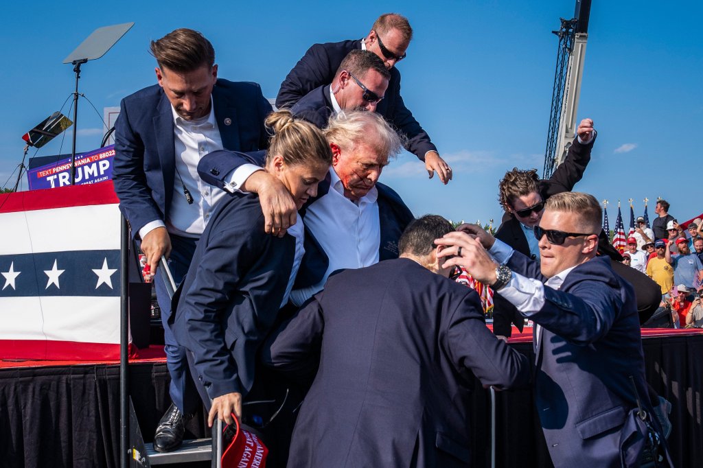 Butler, PA - July 13 : U.S. Secret Service agents remove Republican presidential candidate former president Donald Trump from the stage with blood on his face during a campaign rally at Butler Farm Show Inc. in Butler, PA on Saturday, July 13, 2024. Trump later shared that a bullet pierced part of his ear during the assassination attempt. (Photo by Jabin Botsford/The Washington Post via Getty Images)