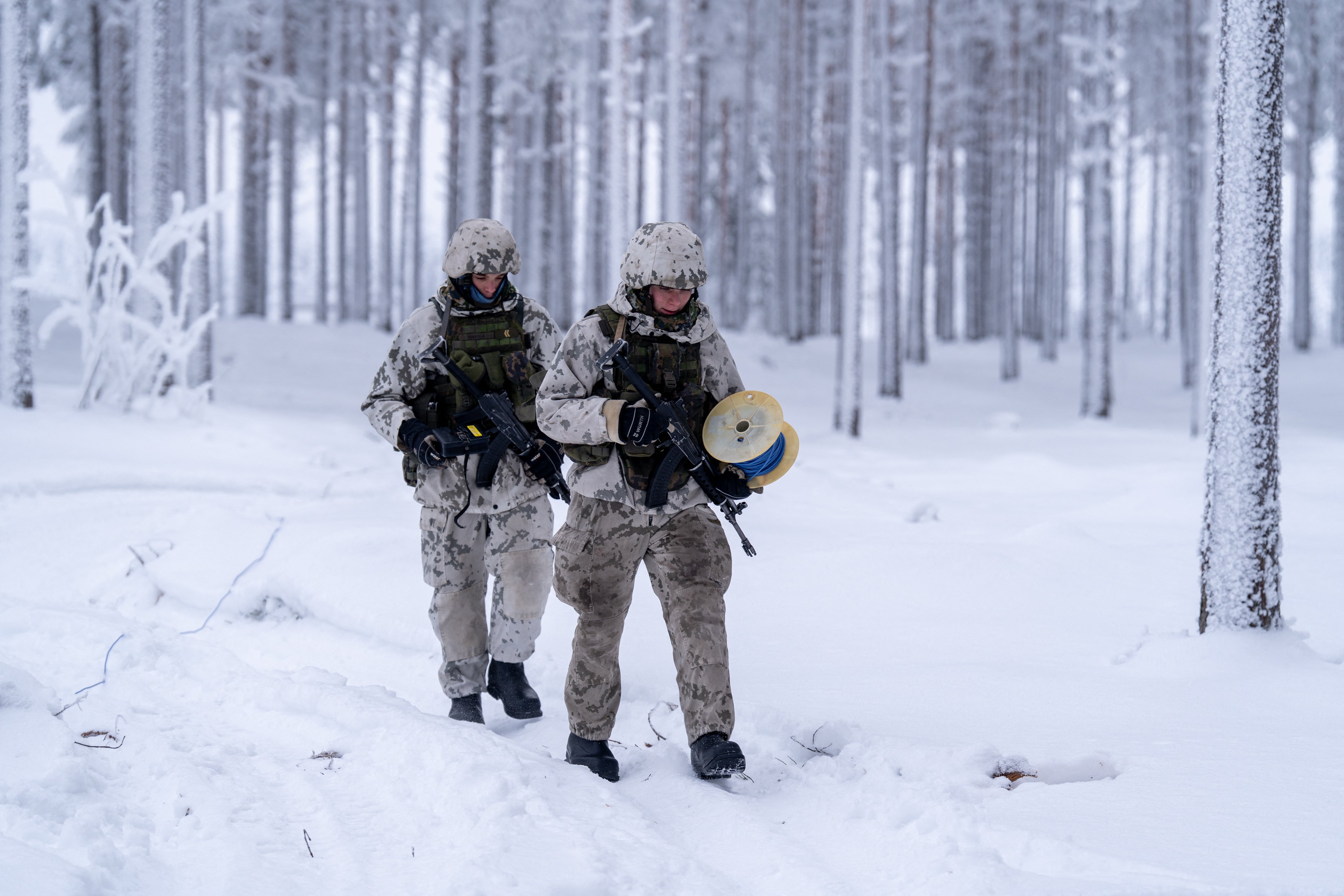 Two Finnish conscripts wearing winter camouflage uniforms, armed with machine guns walk through the snow covered forest while installing anti personnel mines during a media day event at the Kainuu Brigade, a Finnish Army unit in Kajaani, Finland on February 3, 2026. (Photo by Alessandro RAMPAZZO / AFP via Getty Images)