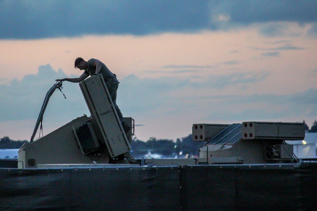 A military service member stands atop a mobile air defense system deployed on the tarmac near a C-17 Globemaster transport aircraft at President Donald J. Trump International Airport (DJT) in West Palm Beach, Florida, on October 15, 2026. The air defense units were staged on the airfield to secure the airspace ahead of the president's upcoming weekend arrival at Mar-a-Lago. (Photo by Christopher Beckett/NurPhoto via Getty Images)